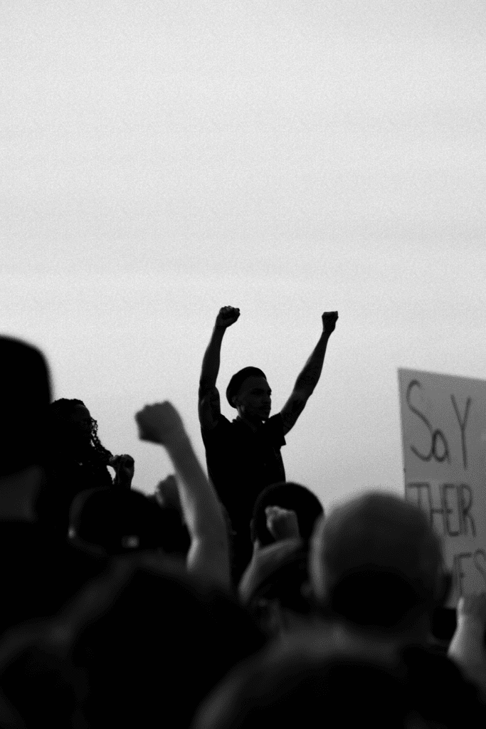 a person with both of their fists in the air protesting